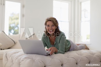 Portrait happy senior woman using laptop on ottoman
