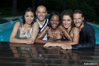 Portrait happy well-dressed couples in swimming pool