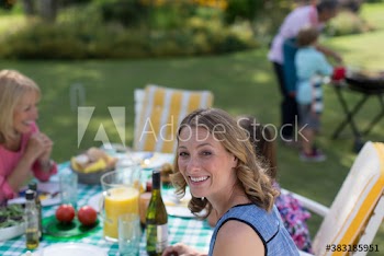 Portrait happy woman enjoying lunch on patio with family