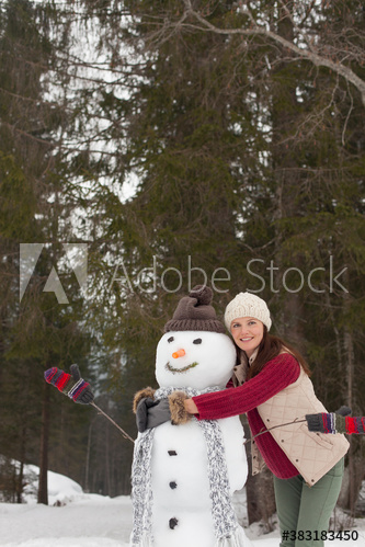 Portrait happy woman hugging snowman in snowy woods