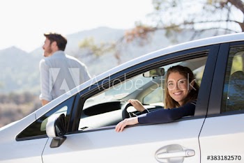 Portrait happy woman inside car at sunny roadside
