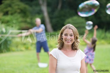 Portrait happy woman playing with bubbles with family in backyard