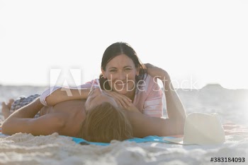 Portrait happy woman relaxing on beach with boyfriend