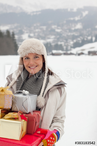 Portrait happy woman with Christmas gifts in snowy field