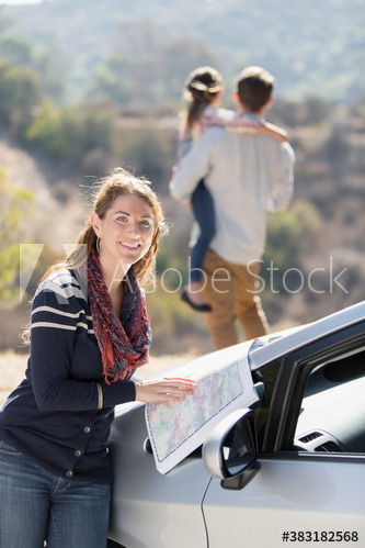 Portrait happy woman with map outside car at sunny roadside