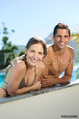 Portrait happy young couple at sunny poolside