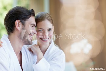 Portrait happy young couple in bathrobes hugging in spa