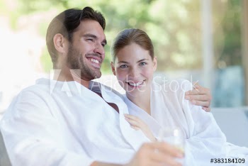 Portrait happy young couple in bathrobes relaxing in spa