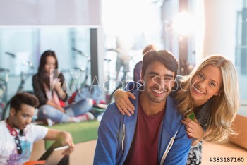 Portrait happy young couple in college student lounge