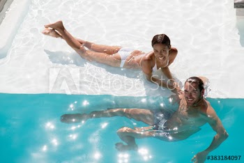 Portrait happy young couple in sunny swimming pool