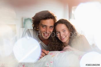 Portrait happy young couple laying on bed