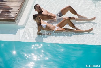Portrait happy young couple relaxing in sunny summer swimming pool