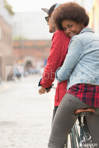 Portrait happy young couple riding bicycle on city street