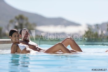 Portrait happy young couple sunbathing in swimming pool