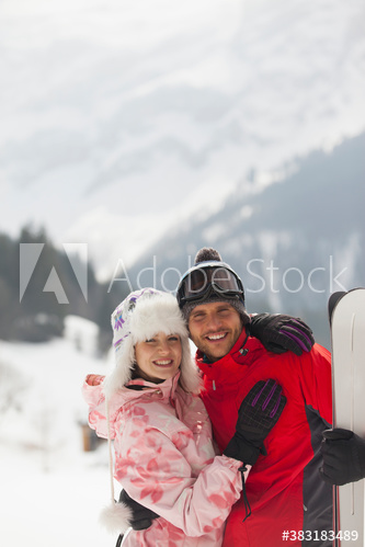 Portrait happy young couple with skis in snow