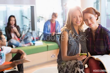 Portrait happy young female college students studying in lounge