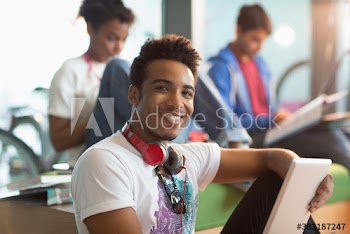 Portrait happy young male college student with headphones using digital tablet