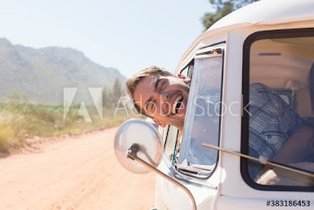 Portrait happy young man leaning out sunny van window