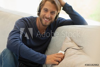 Portrait happy young man listening to music with headphones on sofa