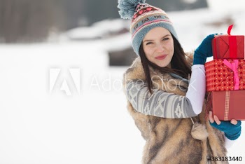 Portrait happy young woman carrying Christmas gifts in snow