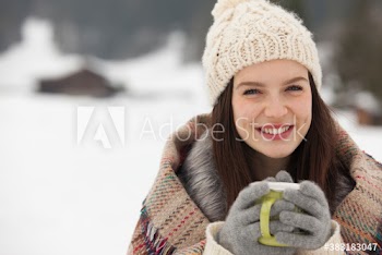 Portrait happy young woman drinking hot cocoa in snow