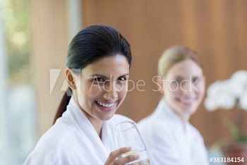 Portrait happy young woman drinking water in spa