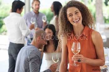 Portrait happy young woman drinking white wine at party with friends