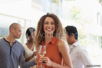 Portrait happy young woman drinking white wine at social gathering