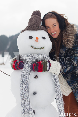 Portrait happy young woman hugging snowman