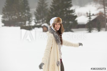 Portrait happy young woman in fur hat walking in snow