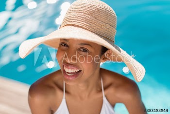 Portrait happy young woman in sun hat at sunny poolside