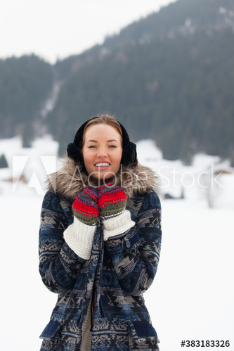 Portrait happy young woman in warm clothing in snowy field