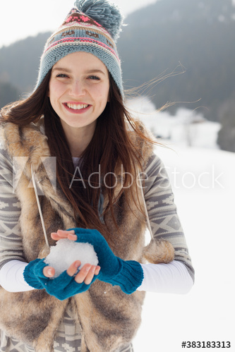 Portrait happy young woman making snowball