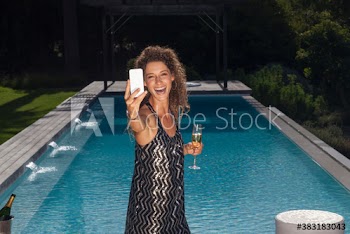 Portrait happy young woman taking selfie with champagne at poolside