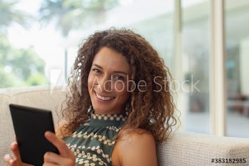 Portrait happy young woman using digital tablet on sofa