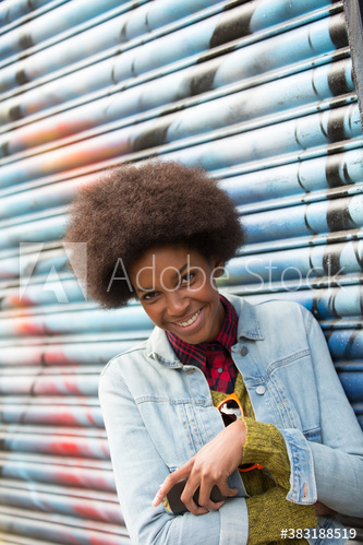 Portrait happy young woman with afro against graffiti wall