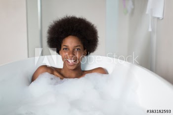 Portrait happy young woman with afro enjoying bubble bath