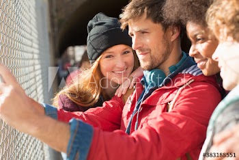 Portrait happy young woman with friends at sunny chainlink fence