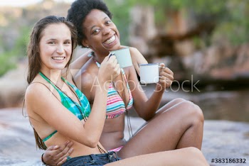 Portrait happy young women friends in bikinis drinking