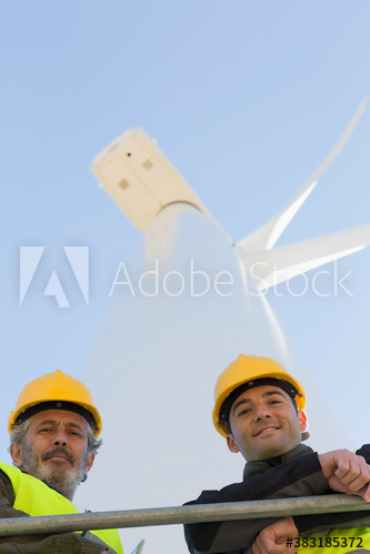 Portrait male engineers below wind turbine