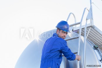 Portrait male worker climbing milk tanker ladder