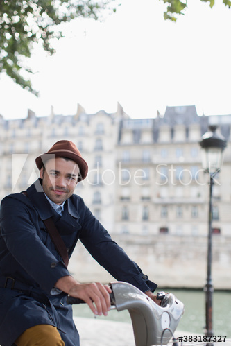 Portrait man riding rented bicycle along Seine River, Paris, France