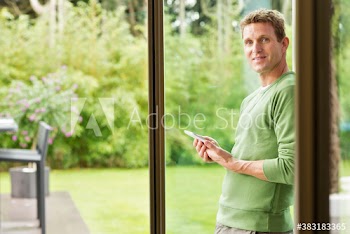 Portrait man using digital tablet at patio window