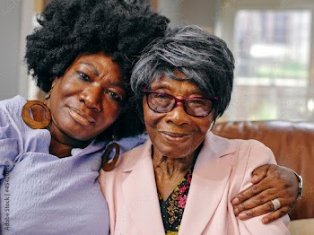 Portrait mature woman embracing senior mother on sofa