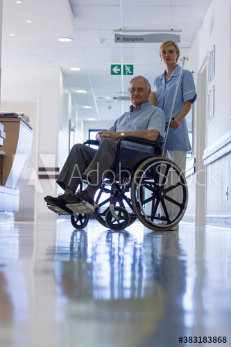 Portrait nurse with senior patient in wheelchair in hospital corridor