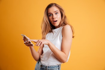Portrait of a confused young girl holding mobile phone Free Photo