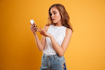 Portrait of a frustrated confused girl looking at mobile phone Free Photo