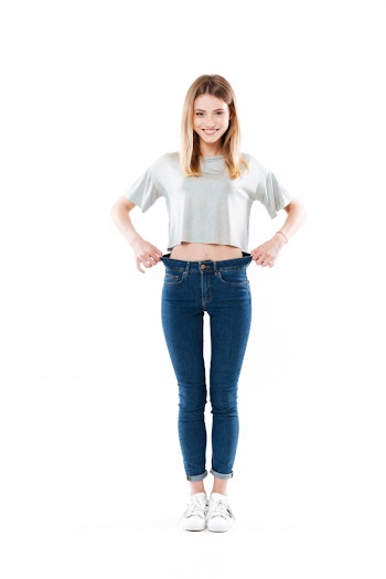 Portrait of a happy satisfied young woman standing and showing her weight loss isolated Free Photo