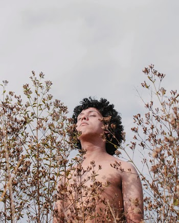 Portrait of a man in the park on the background of natural leaves and branches