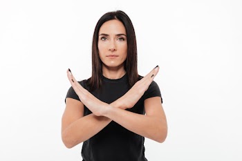 Portrait of a serious young woman showing crossed hands gesture Free Photo